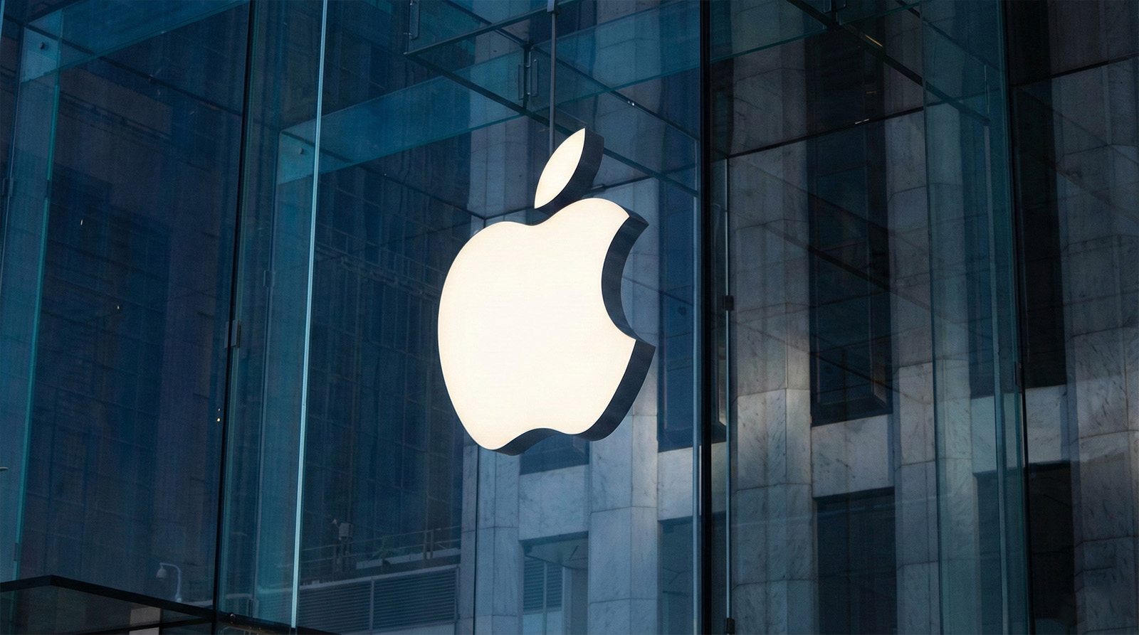 Large glowing Apple logo on a modern glass building facade, symbolizing the brand's global reputation for innovation and minimalist design