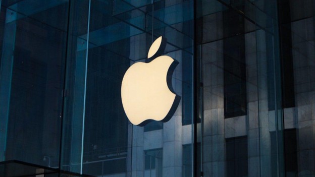 Large glowing Apple logo on a modern glass building facade, symbolizing the brand's global reputation for innovation and minimalist design