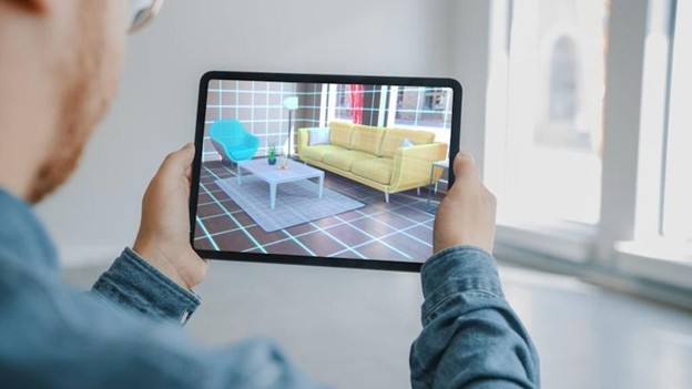 Person using a tablet to view augmented reality furniture in a living room space.