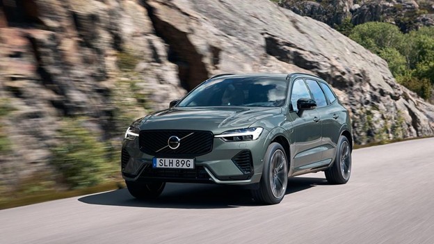 A grey Volvo SUV driving on a scenic road with rocky cliffs, illustrating the brand's consistent positioning around its core value of safety